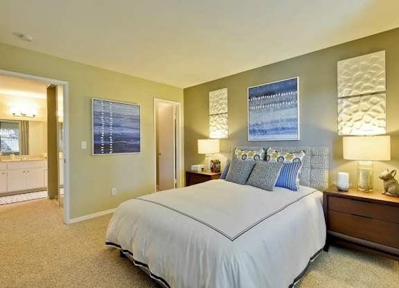 A bedroom with a large bed and a nightstand with a lamp.