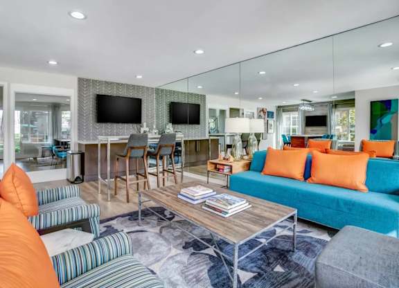 A living room with a blue couch and orange pillows.