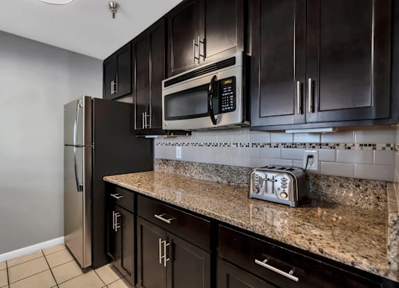 Model Kitchen with Dark Wood Cabinets and Tile Flooring at Misty Ridge Apartments located in Woodbridge, VA.