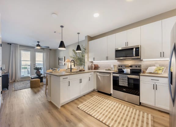an open kitchen and living room with white cabinets and stainless steel appliances