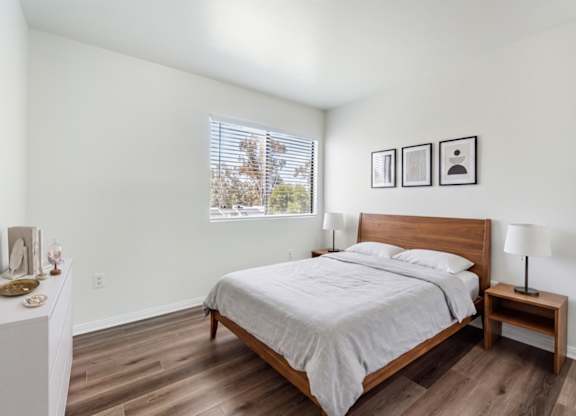 A bedroom with a bed, nightstand, and pictures on the wall.