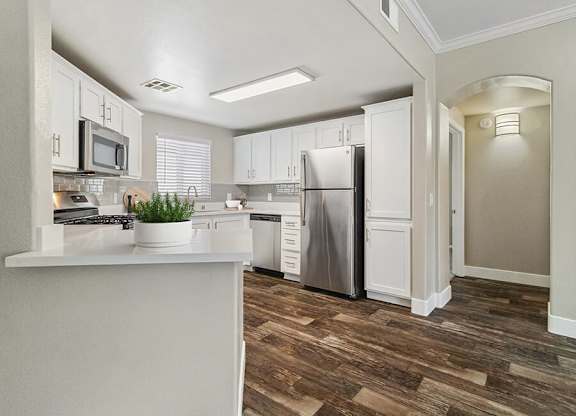 A kitchen with white cabinets and a wooden floor.