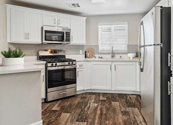 A kitchen with white cabinets and a black refrigerator.