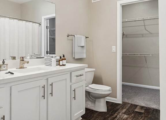 A white bathroom with a toilet, sink, and a mirror.