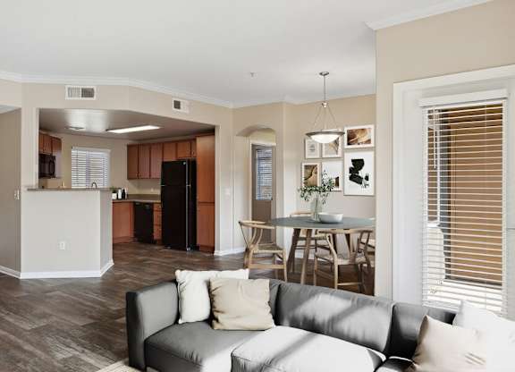 A living room with a grey couch and a kitchen in the background.