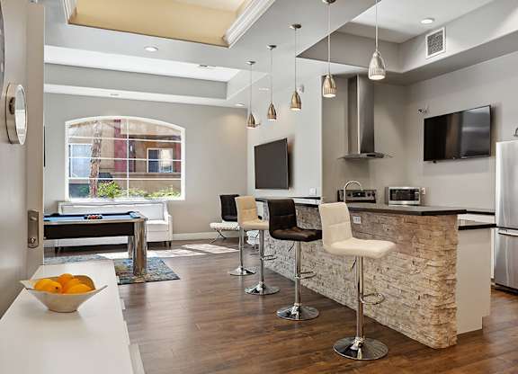 A modern kitchen with a pool table and bar stools.