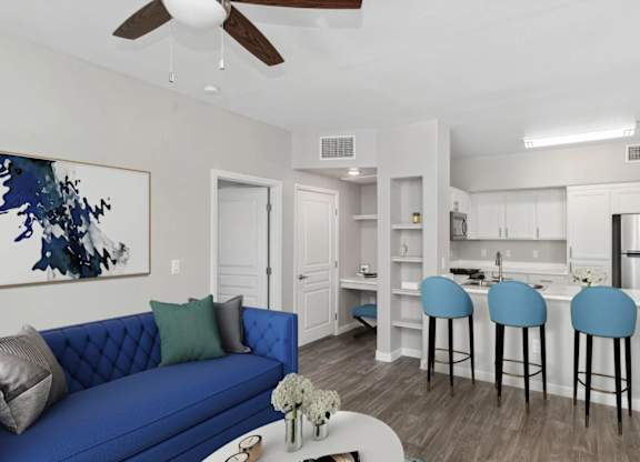 A blue couch with a white vase on a coffee table in a room with a ceiling fan.