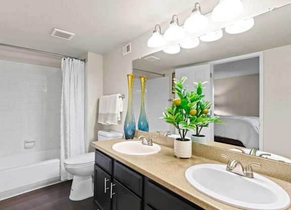 A bathroom with a white tub, sink, and mirror.