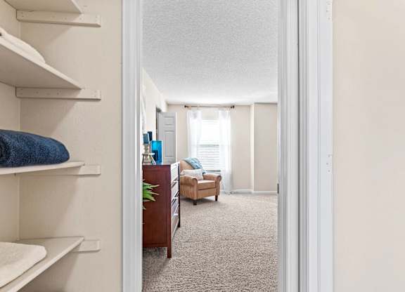 A hallway with a chair and a plant in the background.