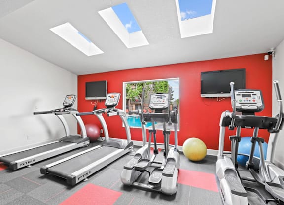 A gym with treadmills, exercise bikes, and a ball.