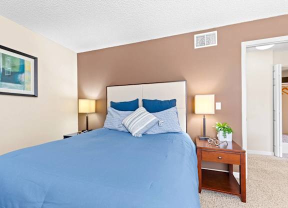 A bed with a blue cover and two blue pillows is in the image.