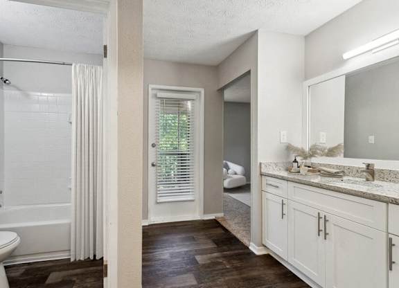 A bathroom with a white tub and a window with blinds.