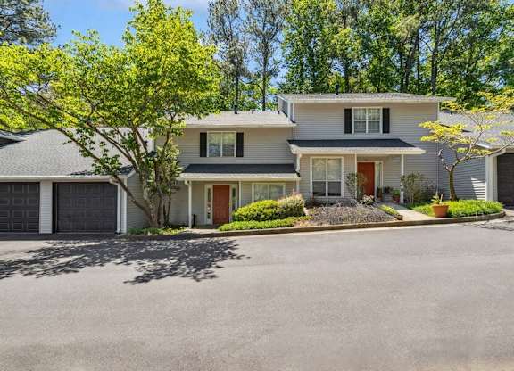 A house with a red door is surrounded by green trees.