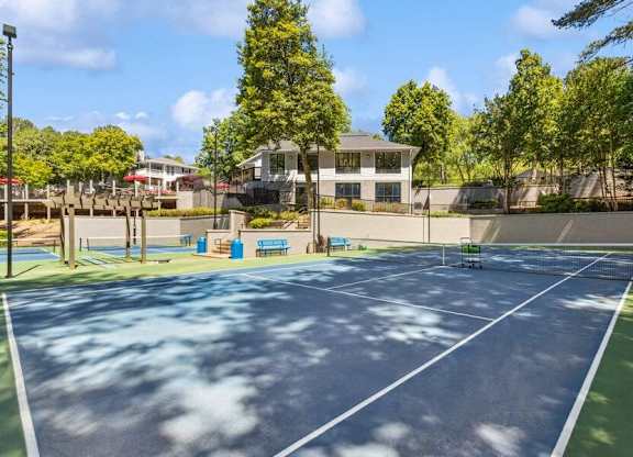 A tennis court with a small building in the background.