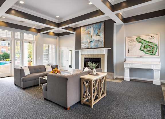 A living room with a grey couch and a white fireplace.