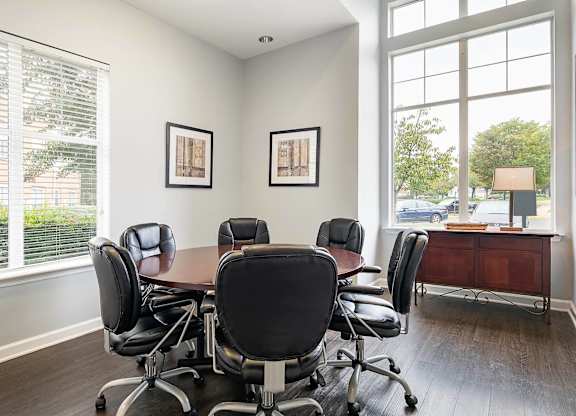 A conference room with a table and chairs and two framed pictures on the wall.