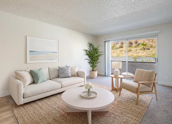 A living room with a couch, chair, and a painting of a beach scene on the wall.