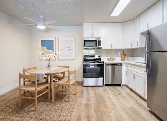A kitchen with a table and chairs and a fridge.