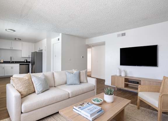 A living room with a white couch and a wooden coffee table.