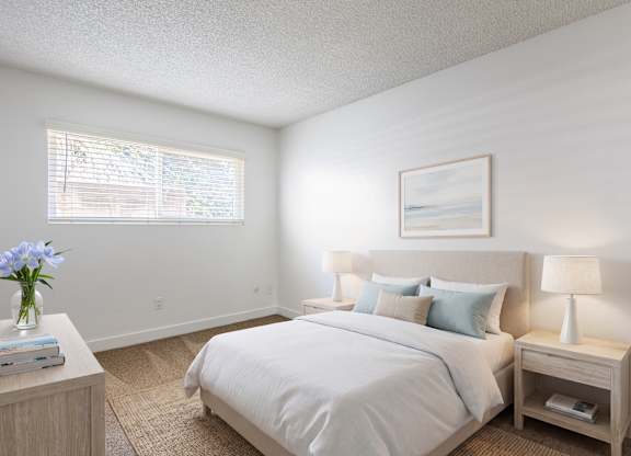 A bedroom with a large bed, a nightstand with a lamp, and a painting on the wall.