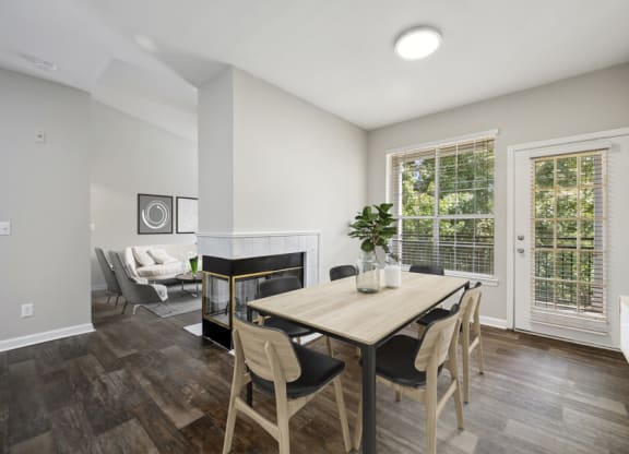 a dining area with a wooden table and chairs and a fireplace in the background