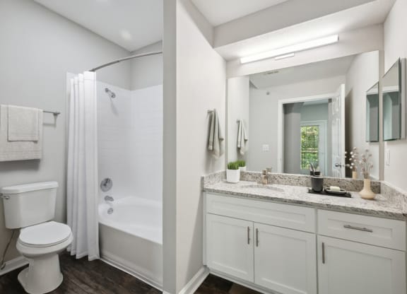 a bathroom with a large mirror and a toilet next to a bathtub with a shower curtain