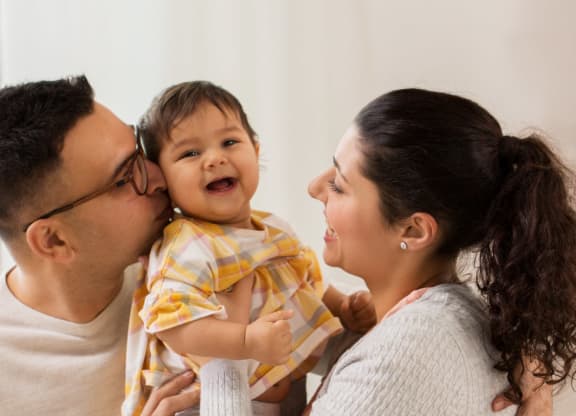 a mother holding a baby and a father kissing a baby