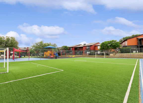 a grass soccer field with a playground in the background