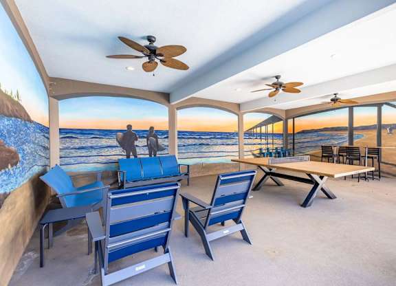 A patio with blue chairs and a table with a view of the beach.