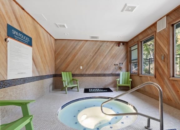 Hot tub spa enclosed with wood panel walls and large windows.