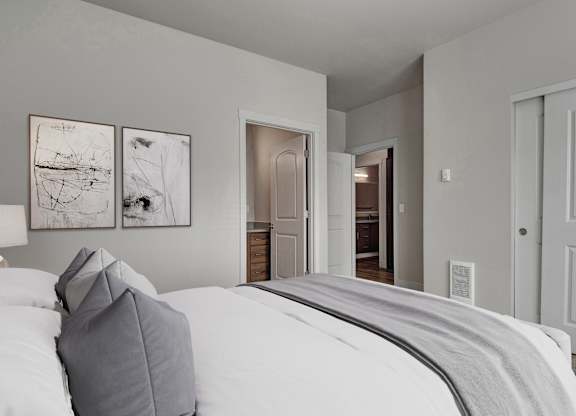 A bedroom with a large bed and two framed pictures on the wall.