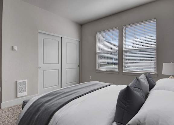 A bedroom with a large bed and two windows.