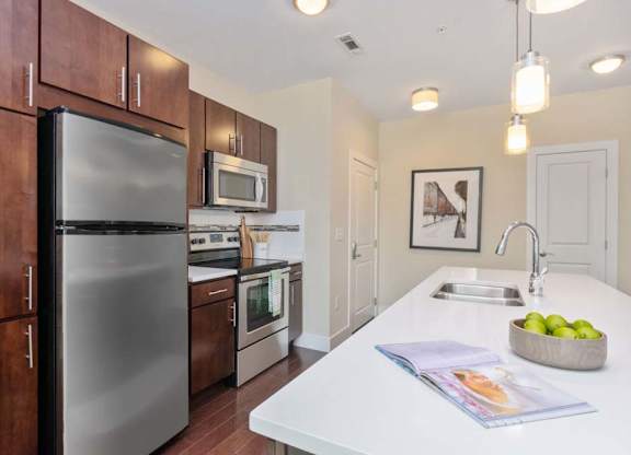 A kitchen with a refrigerator, microwave, oven, and sink.
