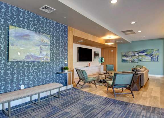 community center with bench, tv, chairs, and blue wallpaper