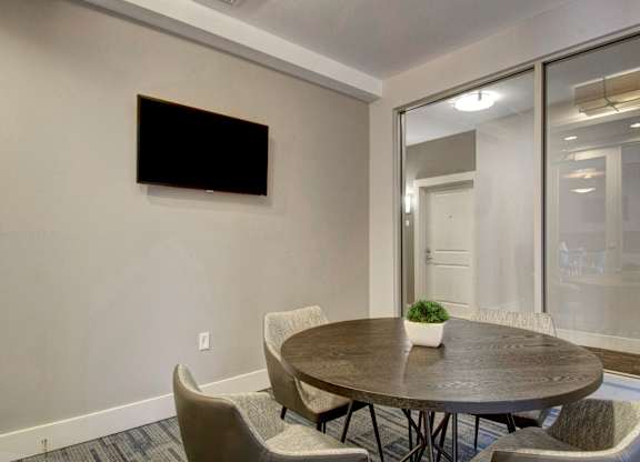 A conference room with a table, chairs, and a television on the wall.