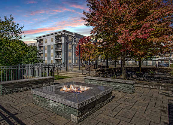 A fire pit sits in the middle of a paved courtyard.