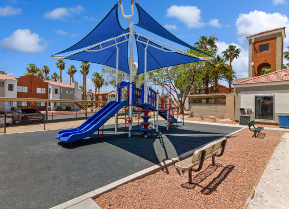 a playground with a blue slide and umbrella at villas at houston levee west apartments