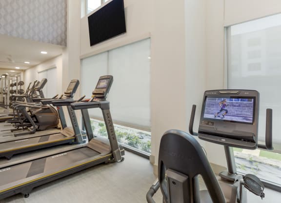 a room filled with cardio equipment and a flat screen tv
