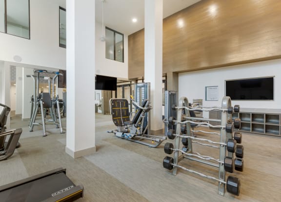 a gym with cardio equipment and a flat screen tv