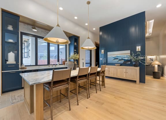 a large kitchen with a long island with chairs and a blue accent wall