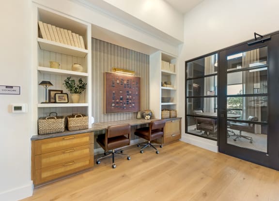 a home office with a large window and a desk with two chairs