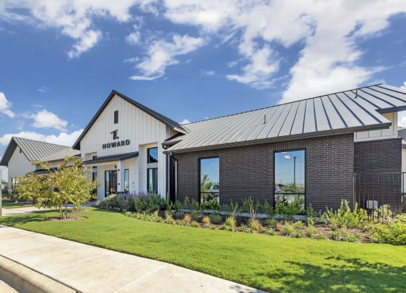 the front of a building with a lawn and a sidewalk
