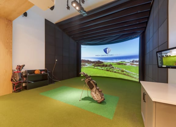 a golf simulator in a room with a tv and a golf bag