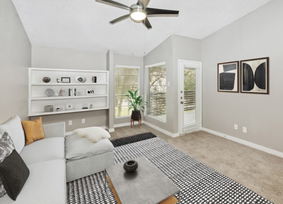 Model apartment living room with a couch and a ceiling fan