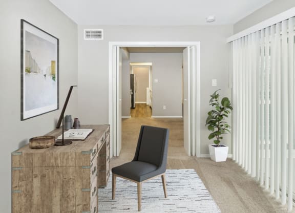 a living room with a desk and a door to a hallway