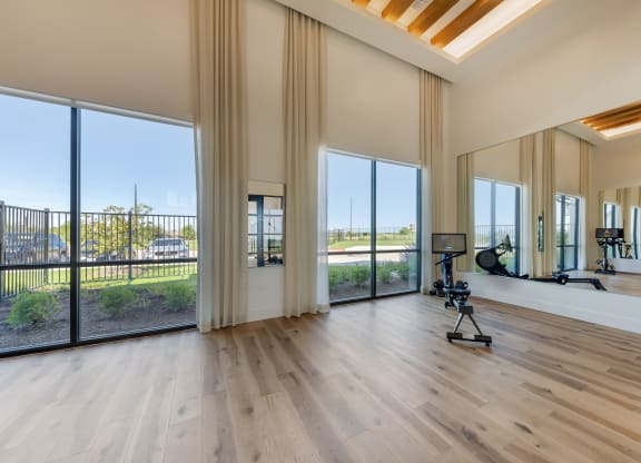 a living room with wood floors and large windows and a workout room