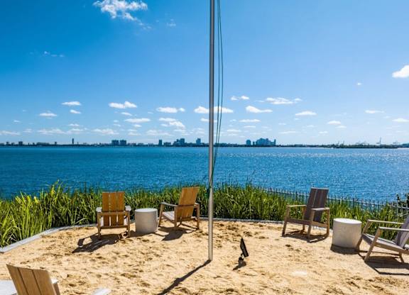a view of the water from a beach with chairs on the sand at The Hamilton, Miami, FL