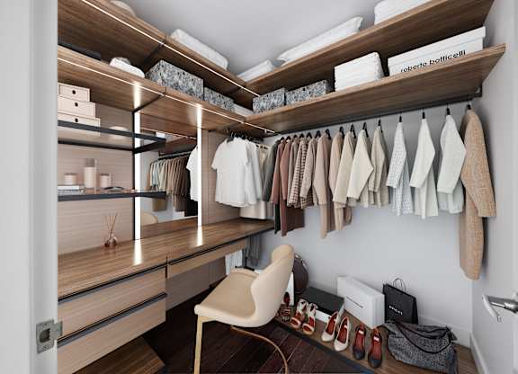 A walk in closet with clothes hanging and shelves with boxes.
