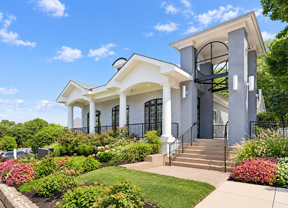 A white house with a black fence and a green lawn.