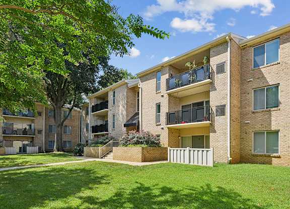 A large apartment building with a green lawn in front.
